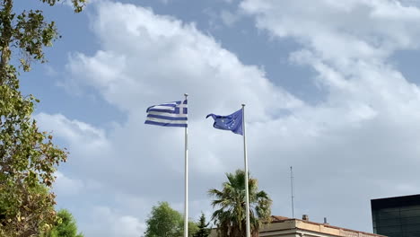 Bandera-Griega-Y-Europea-Ondeando-En-El-Viento,-Fondo-De-Nubes-Blancas