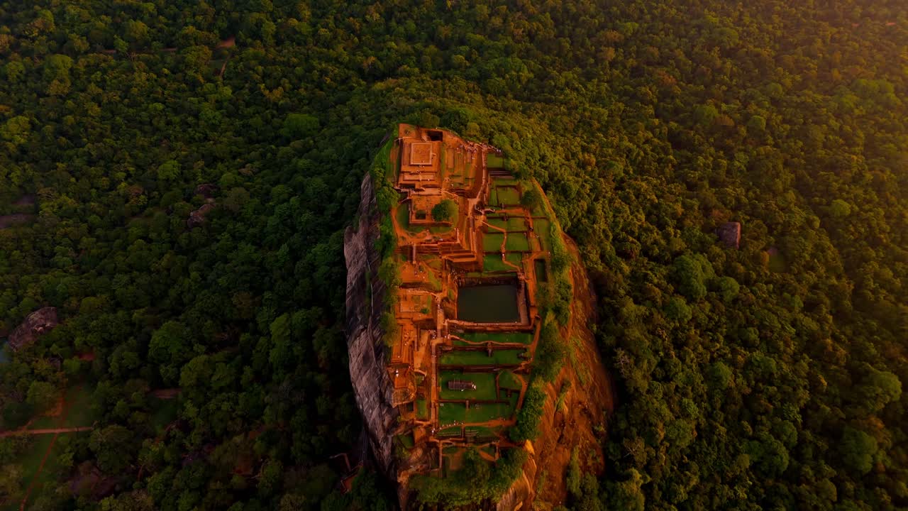 A breathtaking aerial vertical view of Sigiriya Rock at dawn, with the ancient fortress illuminated by the soft first light of the day.