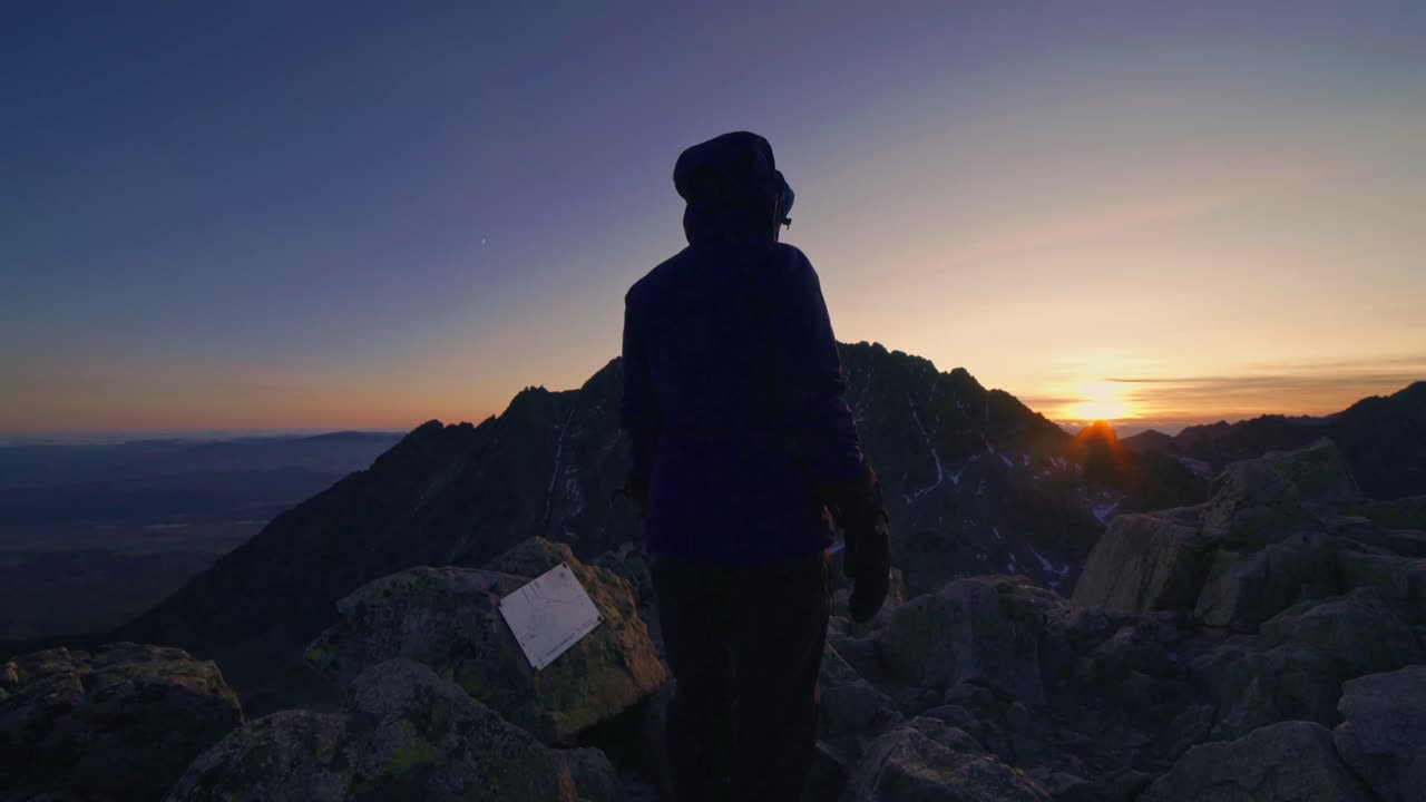 Joy from the beautiful sunset on top of the mountain. Tourist girl jumping at the mountain peak, High Tatras