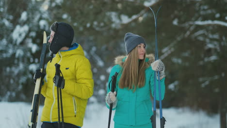 full length portrait of active young couple enjoying skiing in snowy winter forest, focus on smiling woman in front, copy space