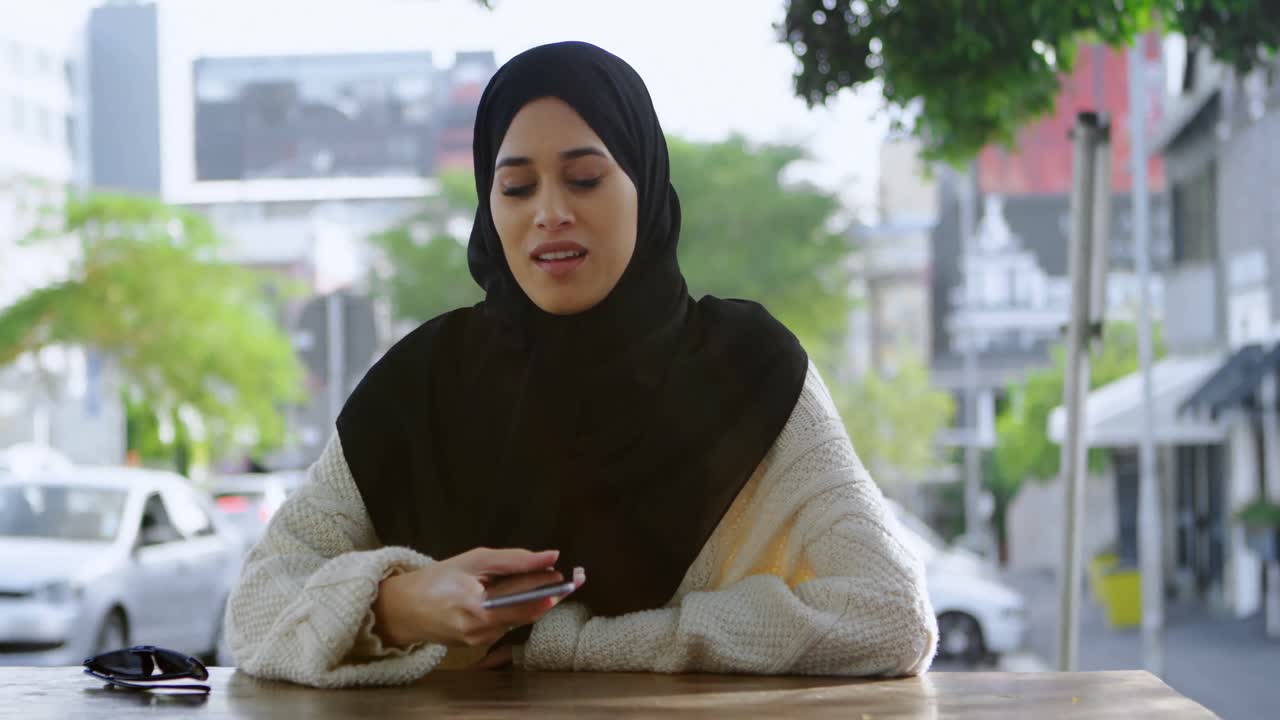 mujer con hijab hablando por teléfono en un café al aire libre 4k