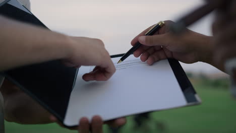 businessman hands sign paper deal on nature. investors write contract outdoors.