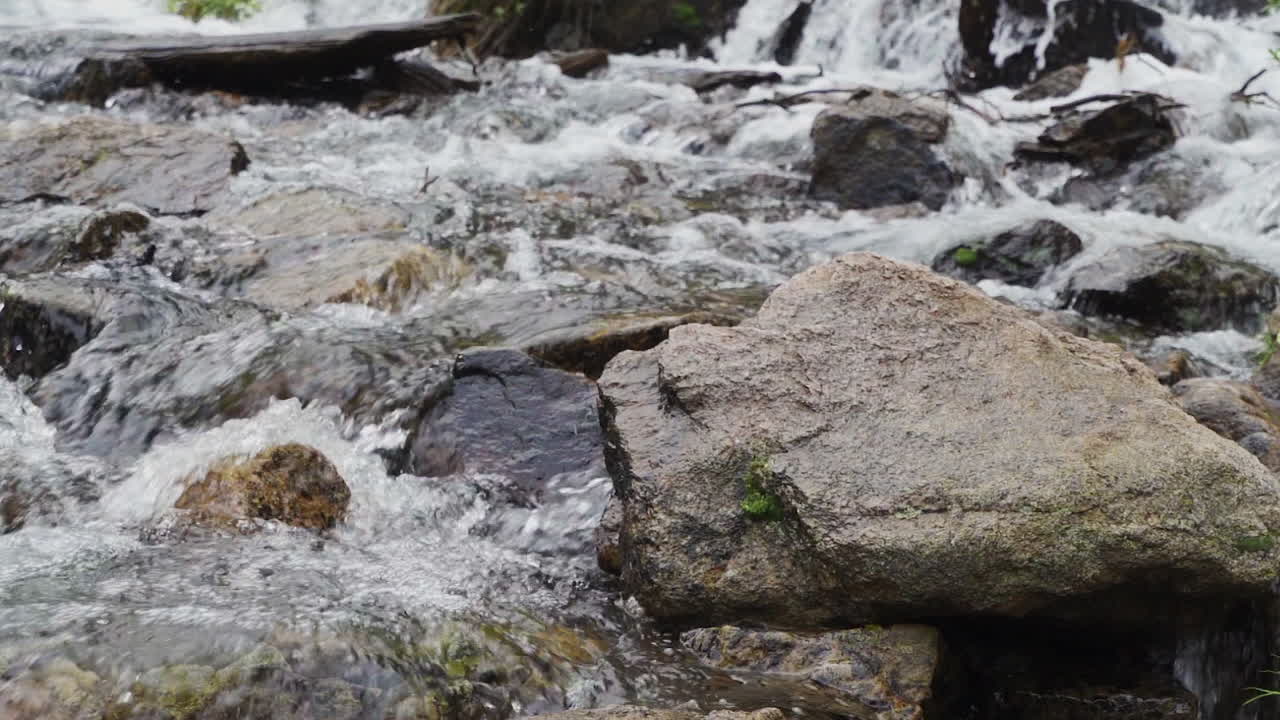 Slow motion white water pouring around rocks