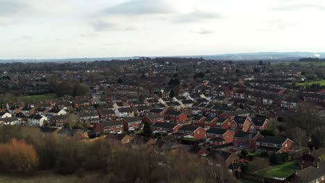 Rural-British-townhouse-neighbourhood-homes-with-green-space-aerial-view-across-to-Snowdonia-mountain-skyline,-rising-forward-shot