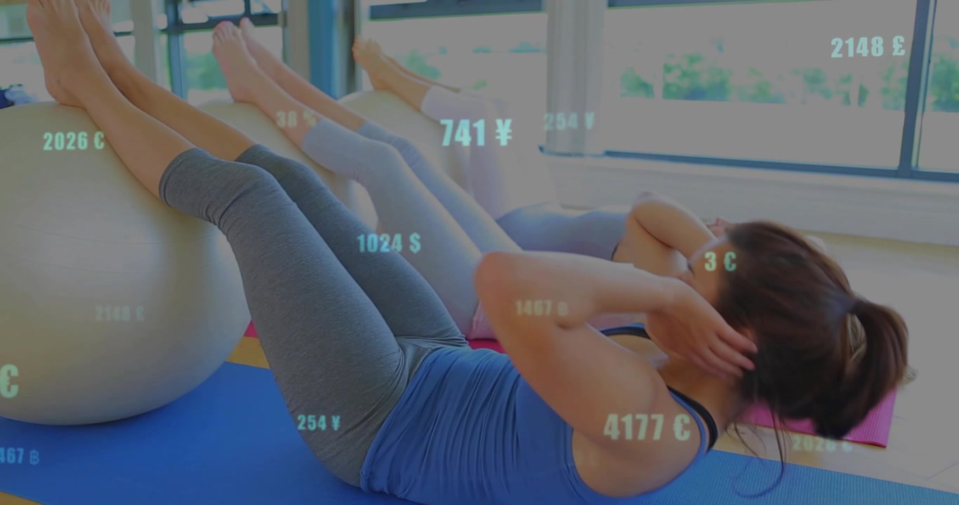 Tres mujeres en clase de fitness, realizando abdominales con las piernas sobre una pelota plateada, con superposición numérica sobre ellas.