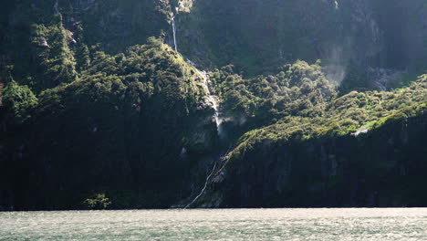 water sprays from waterfall by strong wind in milford sound, new zealand