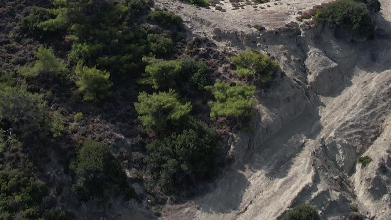 Aerial view of rocky terrain in Greece with shrubs and livestock