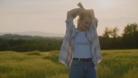 la mujer se alegra bailando con las manos en alto contra el atardecer dorado