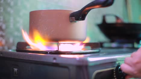 cocina un pequeño quemador encendiendo la estufa, cocinando la llama del hogar, la mano enciende el gas natural con la sartén