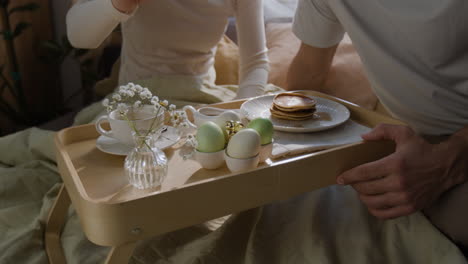 casal a desfrutar do pequeno-almoço de páscoa na cama