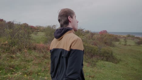 young tall scandinavian guy exploring vårhallarna in simrishamn, sweden österlen - tracking wide shot to medium shot