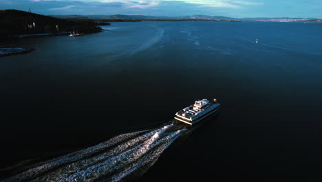 aerial view following a car-ferry heading out on the oslofjord, evening in norway