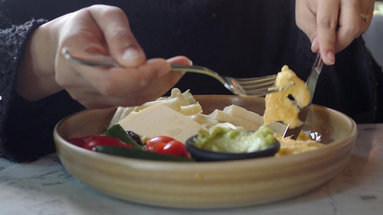 Person Eating Breakfast with Cheese and Vegetables