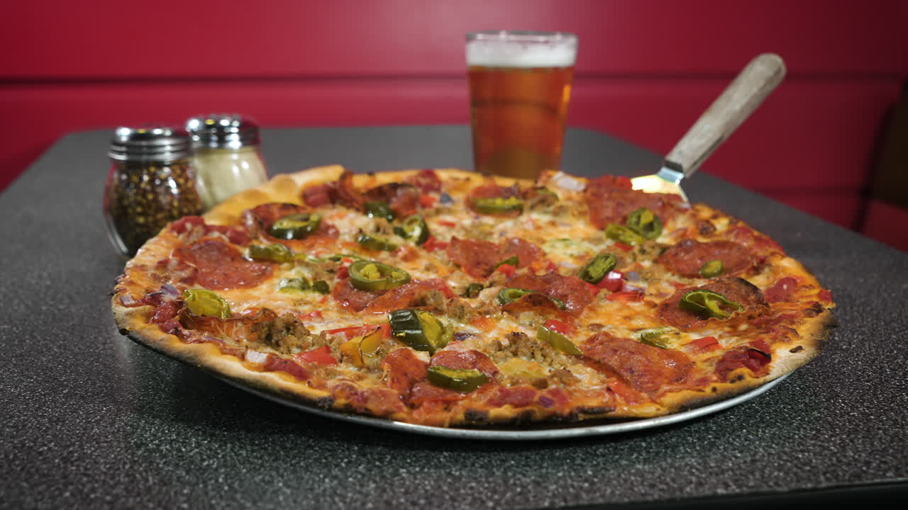 Premium stock video Classic pepperoni pizza in grey pizzeria table top paired with pint of