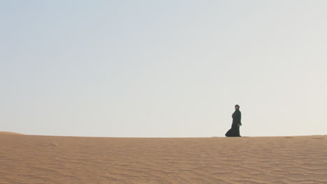 mujer musulmana con hiyab caminando por el desierto