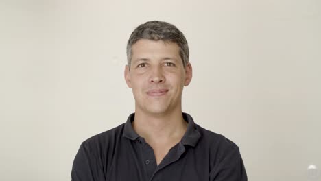 positive handsome caucasian man standing against white wall