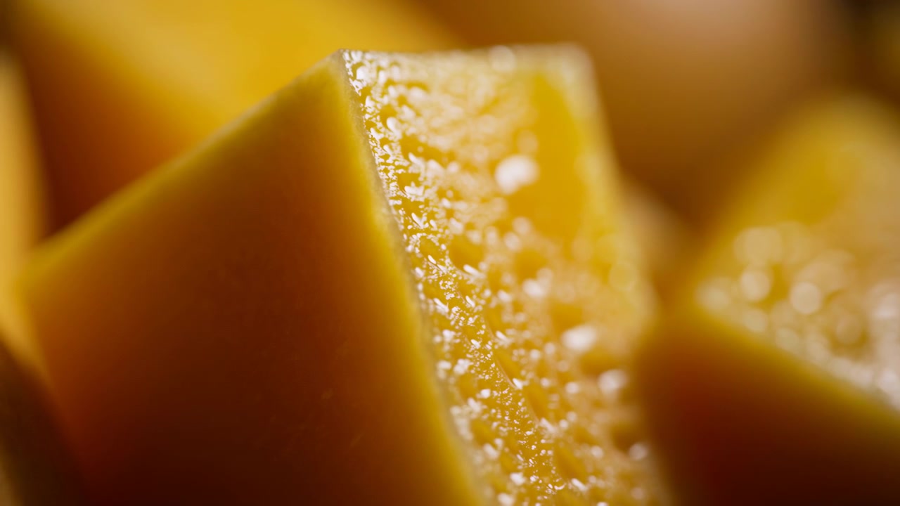 Vista macro dettagliata di spicchi d'arancia affettati con uno spicchio centrale, vescicole di succo dense, polpa lucida e goccioline scintillanti sotto una calda luce ambrata per una texture alimentare fresca e vibrante, con arancia, agrumi.