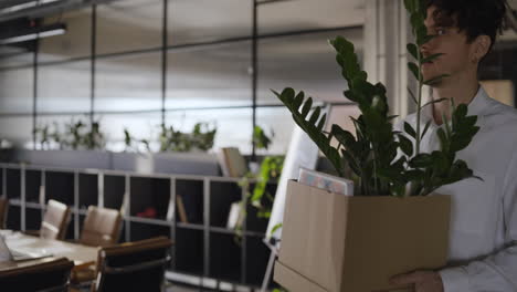 employee leaving the office with box and plant