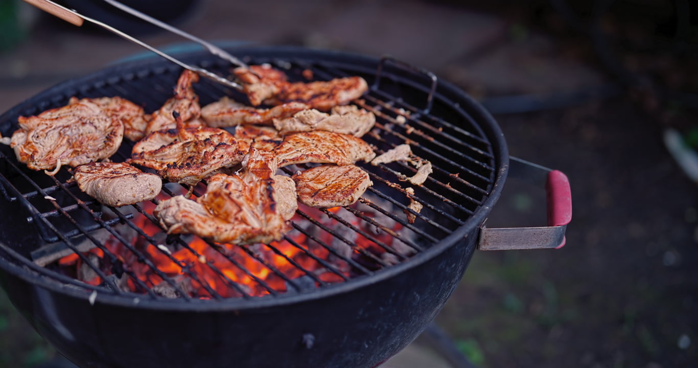 A smooth camera glide reveals chicken cooking over glowing red coals on a worn, well-used backyard grill, capturing the warmth, texture, and honest feel of a real homemade barbecue.