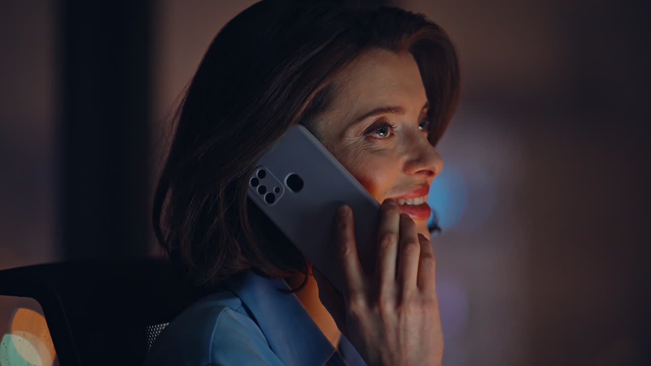 Ritratto di donna d'affari che telefona con il cellulare in ufficio di notte. Donna sorridente