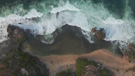 aerial view directly above ocean waves breaking onto sand at tropical beach of indonesia