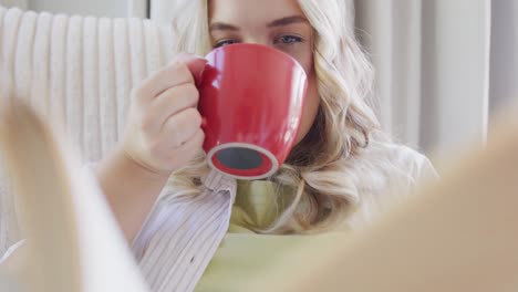 Glückliche-Kaukasische-Plus-Size-Frau,-Die-Ein-Buch-Liest-Und-Kaffee-In-Zeitlupe-Trinkt