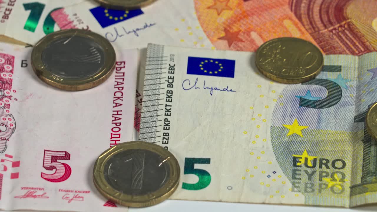 Various Euro banknotes and coins on a white surface in natural light