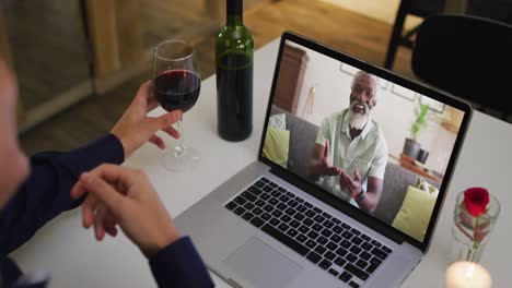 Mid-section-of-african-american-woman-drinking-wine-while-having-a-video-call-on-laptop-at-home