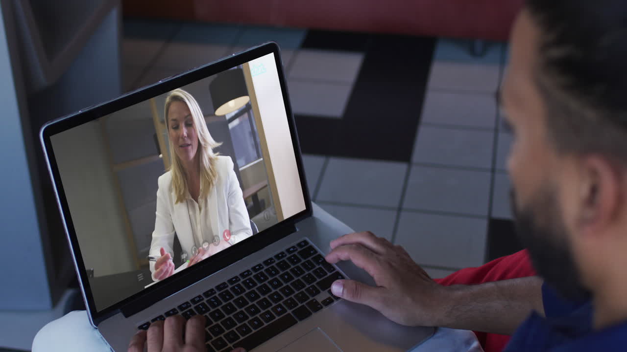 hombre de oriente medio haciendo una videollamada con una colega en una computadora portátil