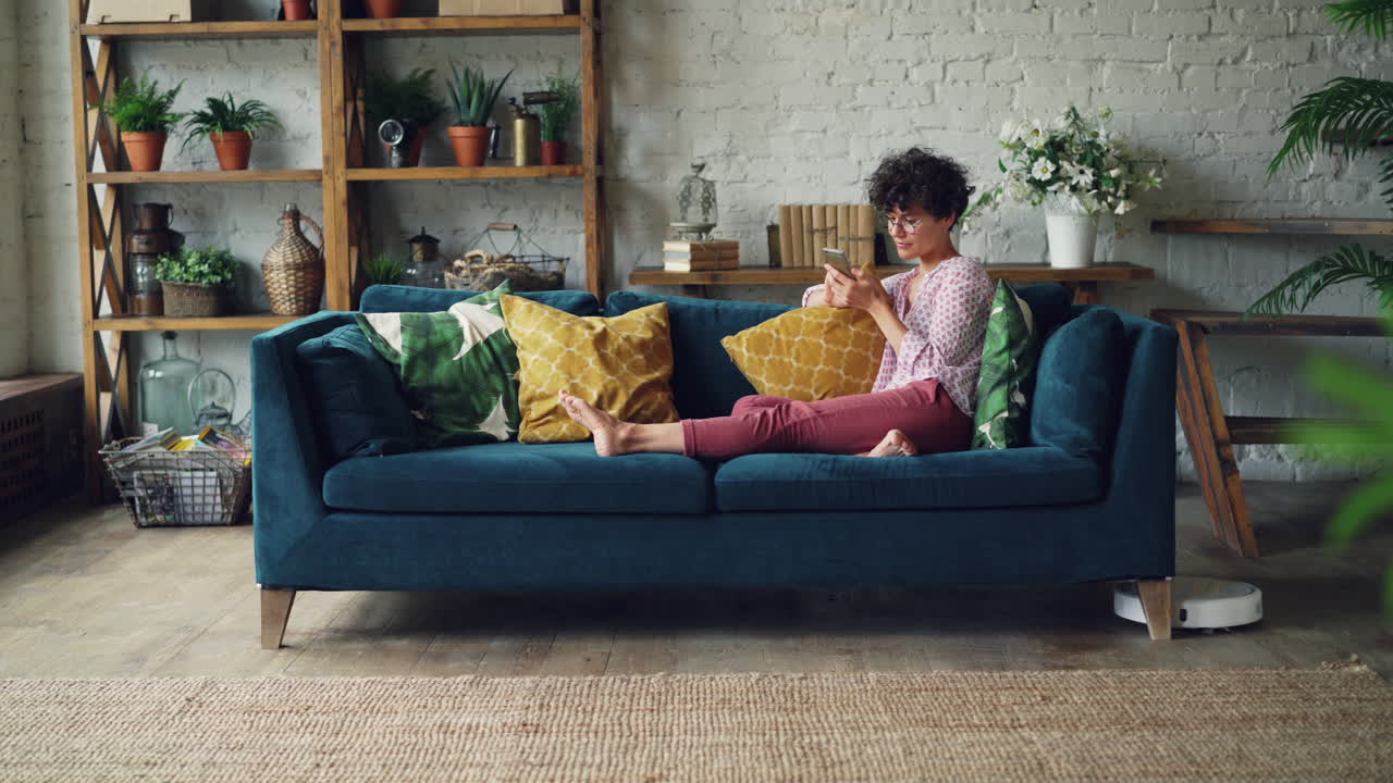 Woman Relaxing on Sofa with Smartphone