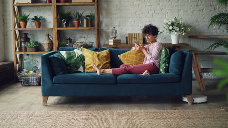 woman relaxing on sofa with smartphone
