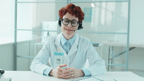 female doctor in headset speaking at camera via online call