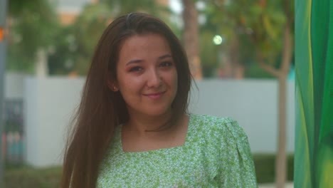 mujer sonriendo con una sonrisa perfecta y dientes blancos en un parque y mirando a la cámara