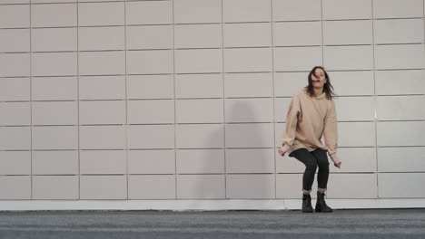 young woman dancing in front of a tiled wall