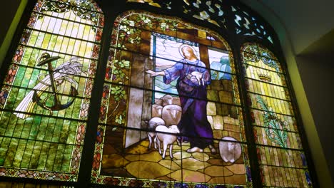 Discover-the-mesmerizing-artistry-of-an-old-stained-glass-window-adorning-the-interior-of-a-historic-church,-casting-vibrant-hues-and-intricate-designs