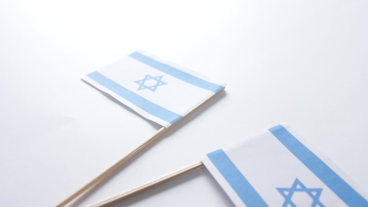 Primo piano di due bandiere di Israele adagiate su sfondo bianco.
