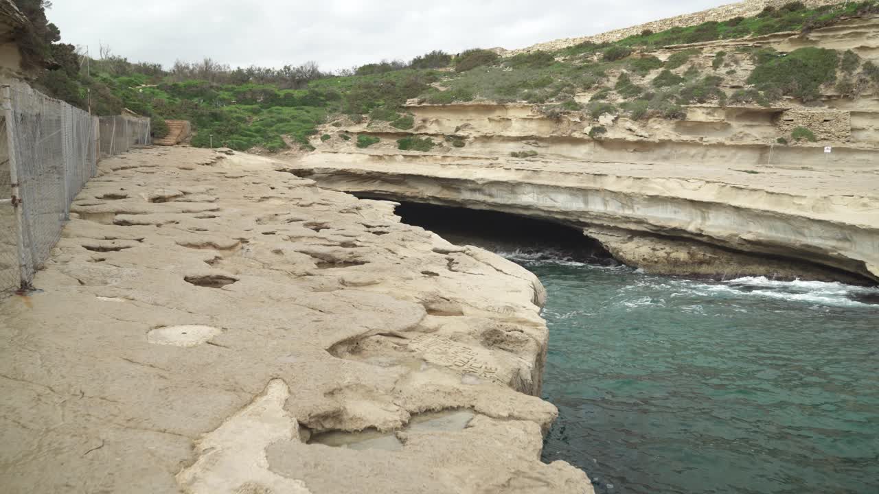cueva de la playa de piedra de la piscina de san pedro sin nadie alrededor solo algo de vegetación escasa en la colina