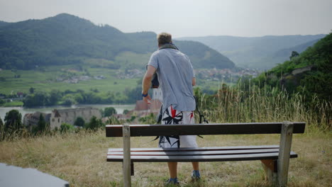 man-looking-over-green-mountain-landscape,-river-danube,-mountains-in-the-background,-hiking-trail,-hills-valley,-hike-trekking-route-Austria-outdoor-walking-route,-male-person-taking-a-break,-rest