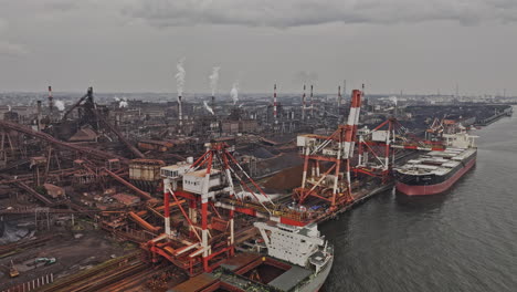 industrial port with steel mill and cargo ships under overcast sky