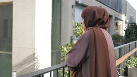 thoughtful woman in brown hijab on a balcony