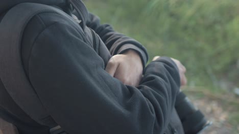 Young-man-sits-with-crossed-arms-on-bench-holding-camera