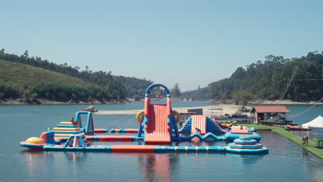 people enjoying on the inflatable outdoor water park in vieira do minho, portugal during summertime - wide shot