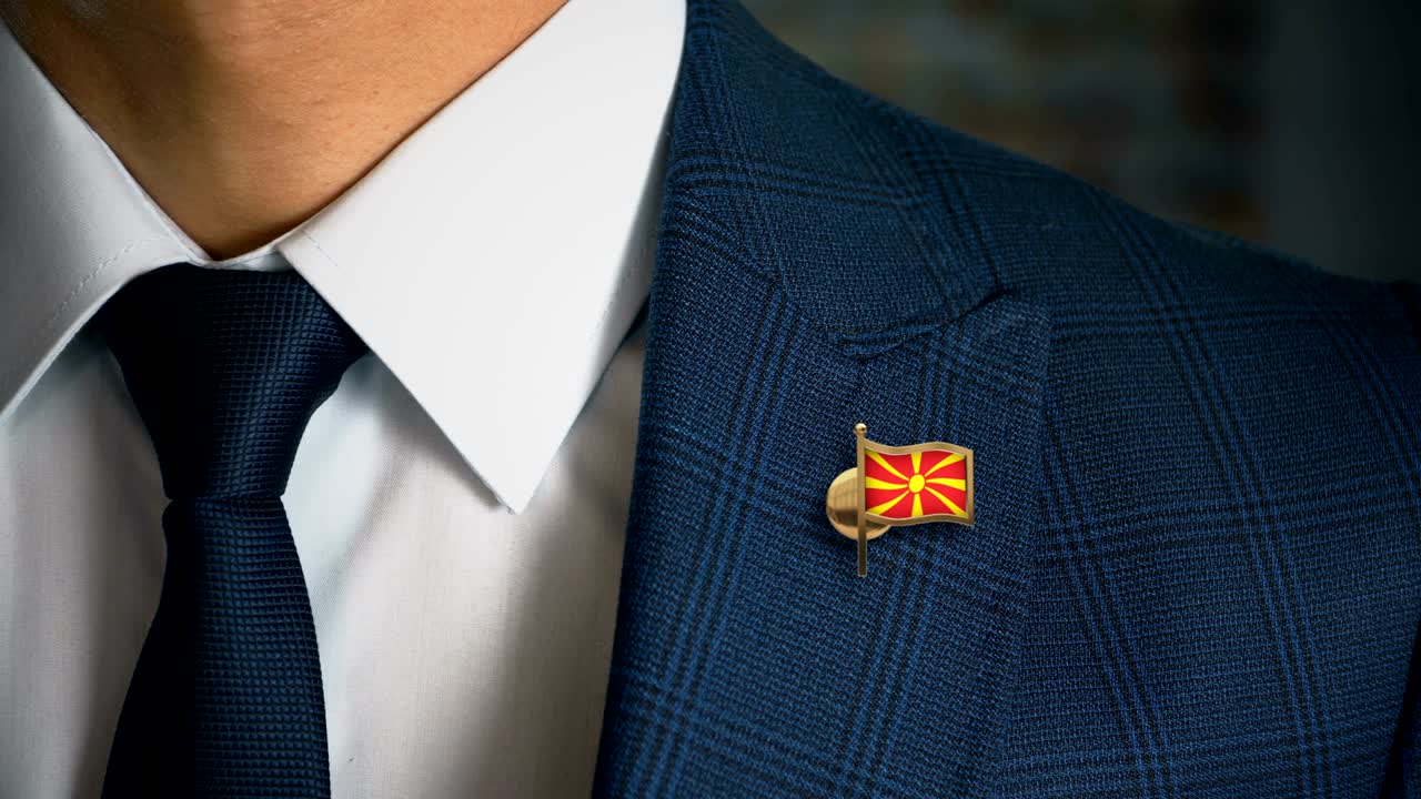 Businessman Walking Towards Camera With Country Flag Pin - Macedonia