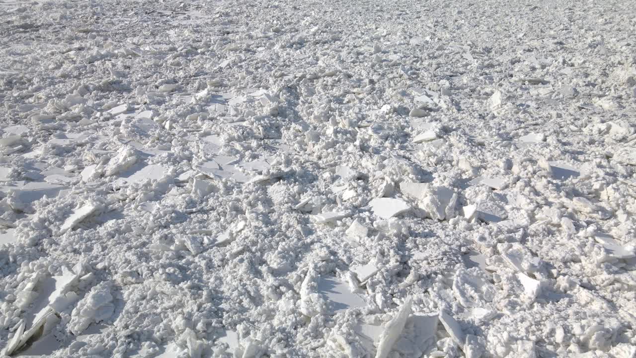 북유럽의 강한 겨울 동안 큰 강을 덮는 금이 간 얼음 타일의 공중 샷