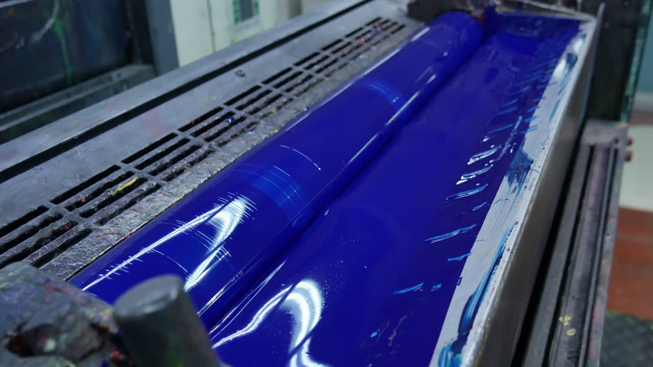 blue paint pot with a roll behind preparing to print some templates for the labels, mass production machine