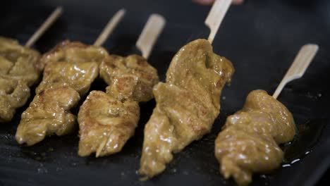 turning gold brown roasted skewers of marinated chicken satay - close up