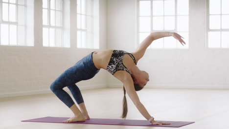 flexible yoga woman exercising practicing one-legged upward bow pose enjoying healthy lifestyle in fitness studio training on exercise mat