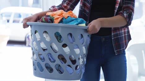 woman carrying clothes in laundry basket at laundromat 4k