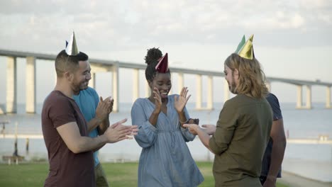 smiling friends congratulating young woman with birthday