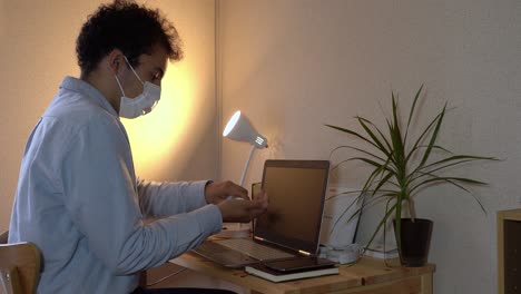 a man using laptop while applying alchohol in his hands to prevent corona virus - mid-shot